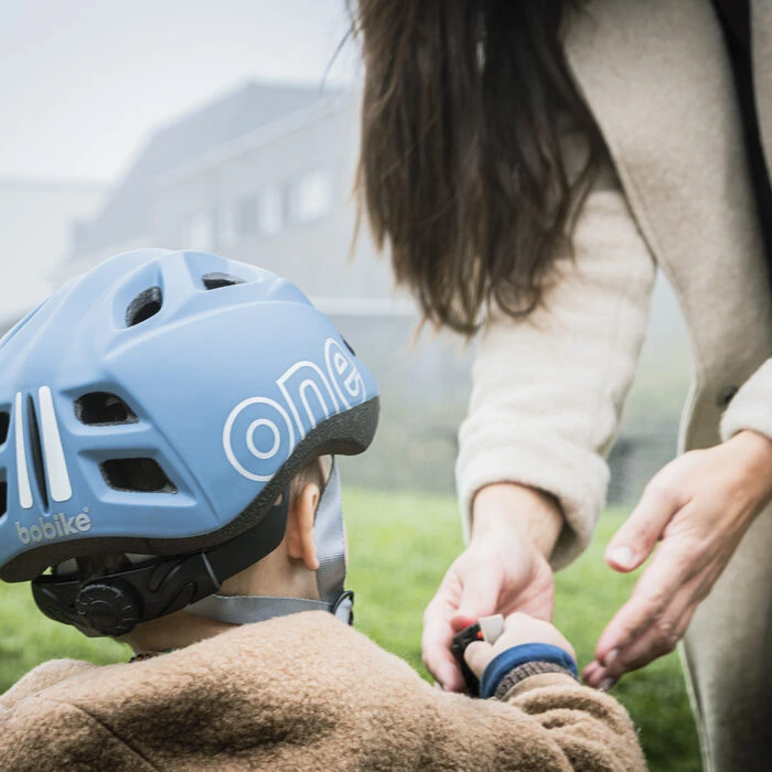 Mujer sujetando la mano de un niño con casco de bicicleta